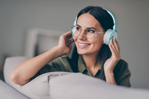 Close-up portrait of charming cheerful lady sitting on divan enjoying listening stereo sound chart at home house flat indoor - Фото, зображення