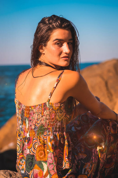 Portrait of a young Caucasian woman from the back with wet hair and a floral dress by the sea, summer lifestyle - Photo, Image