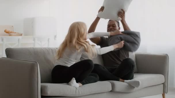 Happy Diverse Couple Having Pillow Fight On Sofa At Home - Materiał filmowy, wideo
