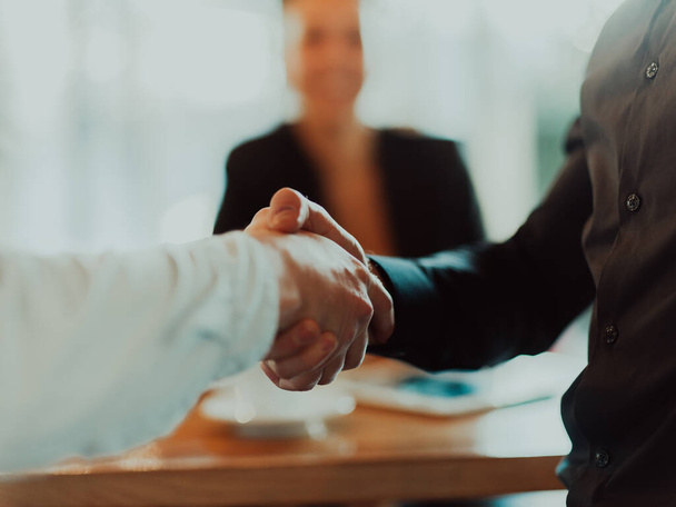 Geschäftsleute oder Anwälte beim Händeschütteln zum Abschluss eines Meetings oder einer Verhandlung im sonnigen Büro. - Foto, Bild