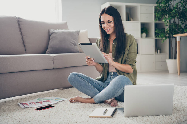 Portrait of pretty focused smart cheerful girl sitting on carpet using device analyzing finance market start-up at home house flat indoor - Fotografie, Obrázek