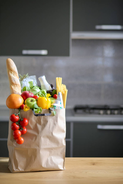 Full paper bag with healthy food on the background of the kitchen.Healthy food background.Supermarket food concept.Milk, bread, fruit.Shopping at the supermarket.World Food Day.Order groceries at home - Photo, Image