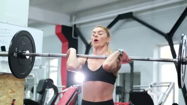 Mujer atlética realizando ejercicios con una barra, levanta un entrenamiento de barra en el gimnasio. - Metraje, vídeo