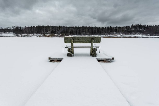 Small woody fishing pier at the lake in winter season. Moody cloudy day.Okuniewo, Pomeranian Voivodeship, Poland. - Fotografie, Obrázek