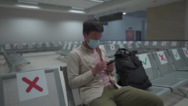 Άνδρας με προστατευτική μάσκα αναστατωμένος από την πτήση ακύρωσης, γράφει μήνυμα στην οικογένειά του, που κάθεται σε άδειο τερματικό σταθμό στο αεροδρόμιο της Κύπρου, στην πόλη Πάφος, λόγω πανδημίας του ιού του Κόβιντ 19 - Πλάνα, βίντεο