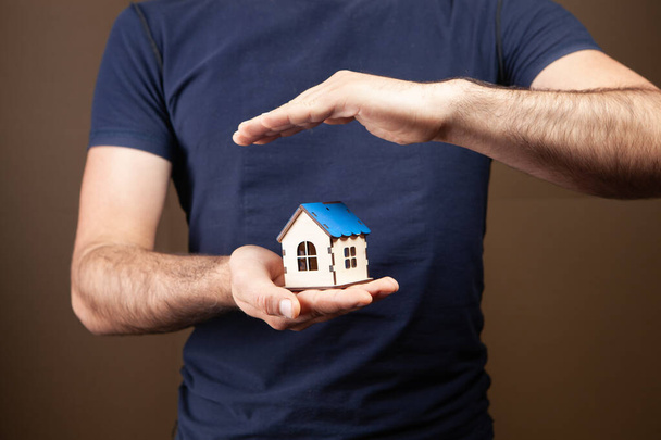 protects the house with his hands on a brown background - Photo, Image
