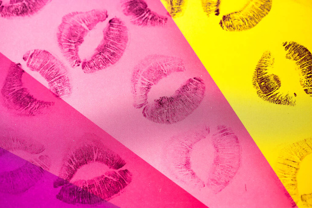 Абстрактні фіолетові червоні губні поцілунки на жовтому рожевому тлі мистецтва. На папері багато відбитків жіночих губ. Відрізняють чудові марки губ. Валентинів день, романтична концепція любові. Поцілунки на помаді. - Фото, зображення