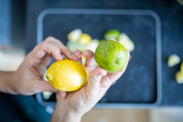 Mains féminines tenant un citron et un citron vert au-dessus des tranches de fruits - Photo, image