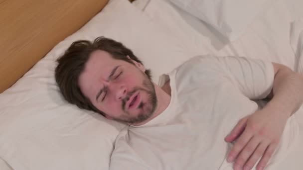 Lässiger junger Mann hustet während er im Bett schläft - Filmmaterial, Video