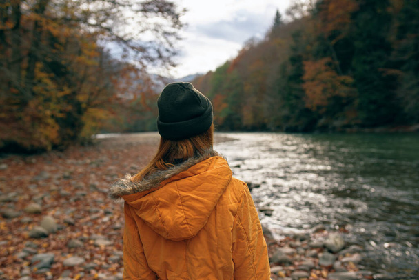 woman hiker admires nature in the mountains autumn river - Фото, зображення