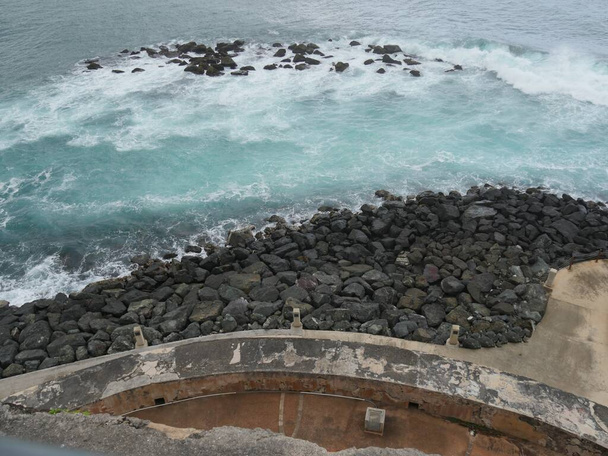 Betonpromenade und felsiger Strand im hinteren Teil des Castillo San Felipe del Morro oder El Morro Fort in San Juan, Puerto Rico. - Foto, Bild