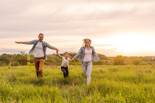 Mutlu aile: anne baba ve kız gün batımında doğada - Fotoğraf, Görsel