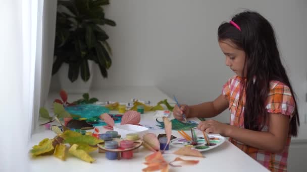 Ζωγραφική κοριτσάκι σε φθινοπωρινά κίτρινα φύλλα με γκουάς, παιδικές τέχνες, παιδική δημιουργικότητα, φθινόπωρο  - Πλάνα, βίντεο