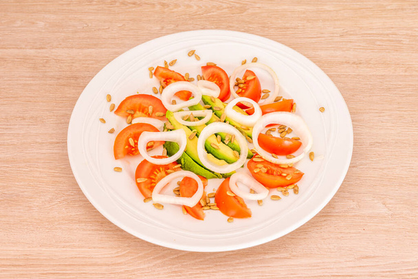 prosta sałatka z awokado z białą cebulą, pomidorem i obranymi nasionami słonecznika - Zdjęcie, obraz