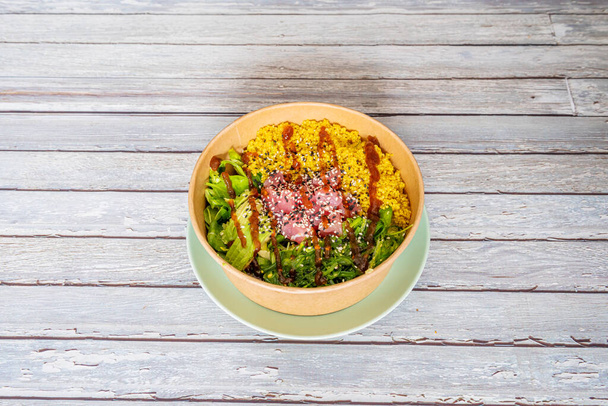 Poke bowl with quinoa, avocado, seaweed, lettuce sprouts, soy sauce in home delivery container - Фото, зображення