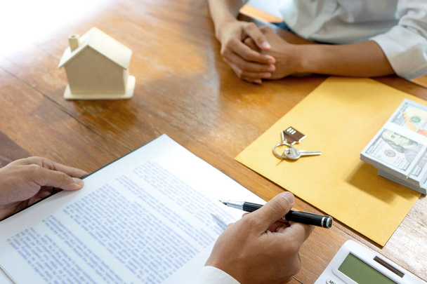 Biznesmen bada kontrakt na dostarczenie domu do klienta na stole są klucze modelu domu i gotówki koncepcji biznesu nieruchomości  - Zdjęcie, obraz