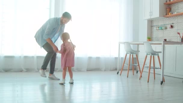 Giovane padre ballerino e piccola ragazza carina in soggiorno. Papà e figlia trascorrono del tempo insieme - Filmati, video