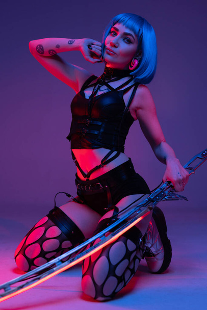 Stylish cyberpunk girl with blue hairs and glowing sword - Fotoğraf, Görsel