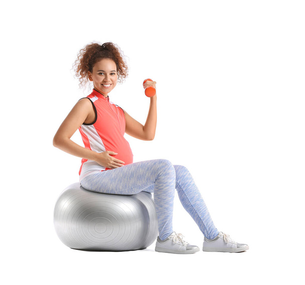 Pregnant woman with dumbbells and fitball training on white background - Фото, зображення