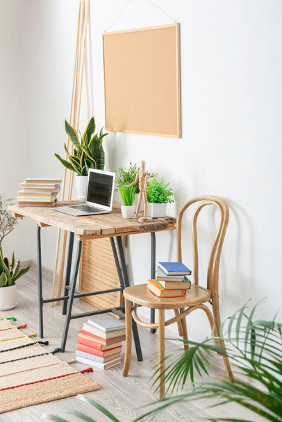 Cómodo lugar de trabajo con libros y plantas de interior de la habitación - Foto, imagen