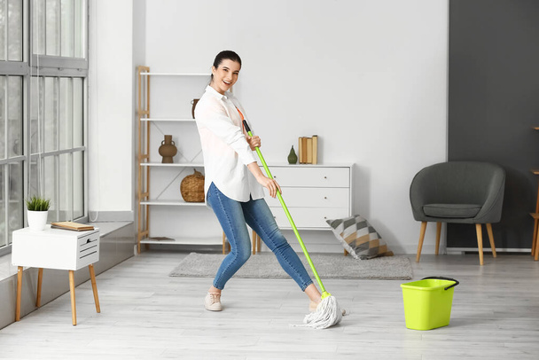 Mladá žena se baví při čištění podlahy v jejím bytě - Fotografie, Obrázek