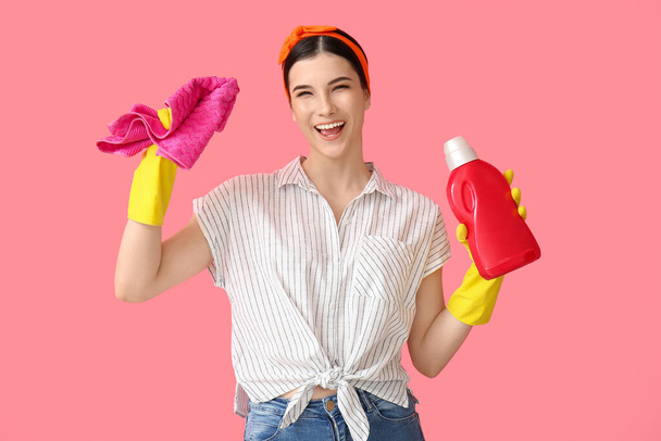 Young woman with cleaning supplies on color background - Photo, Image