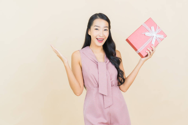Portré gyönyörű fiatal ázsiai nő mosoly piros ajándék doboz színes háttér - Fotó, kép