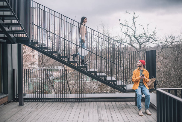 Man sitting on the steps, the girl going down on the bridge - Fotoğraf, Görsel