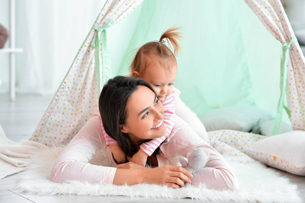 Happy woman and her little daughter playing in wigwam at home - Foto, Imagem