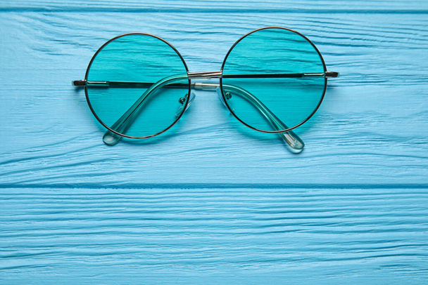 Elegantes gafas de sol sobre fondo de madera de color, primer plano - Foto, imagen