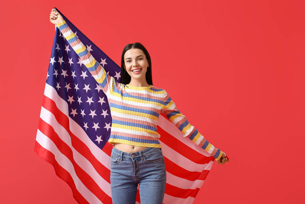 Beautiful young woman with USA flag on color background - Photo, image