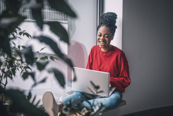 Black woman in red shirt with a laptop - Foto, imagen