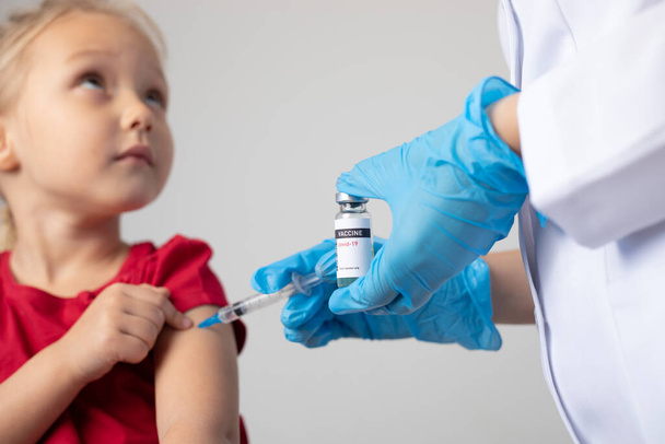 The doctor gives the child an injection of covid-19 vaccine. - Φωτογραφία, εικόνα