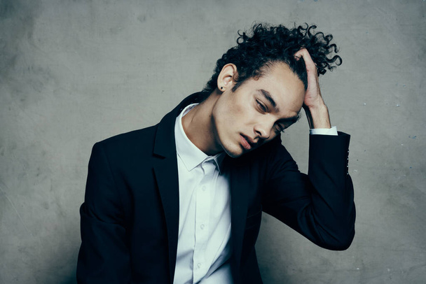 curly haired guy in a suit sitting on a chair fashion modern style jacket - 写真・画像