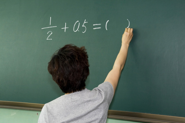 Female teacher writing on a blackboard - 写真・画像