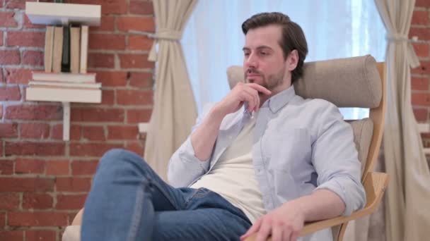 Casual Young Man Sitting on Sofa Thinking - Footage, Video