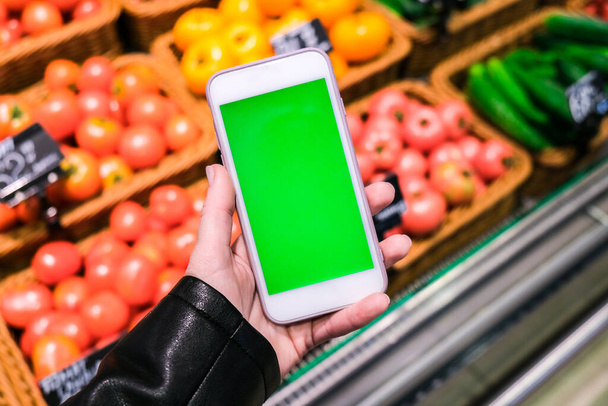 Chroma key. Close up of woman holds smart phone with green screen at grocery store. Shopping center. Department store. Mall. Shopping online. Gadgets - Photo, Image