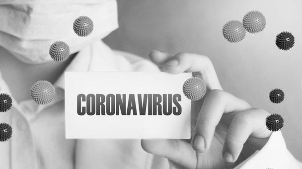 Dokter of medisch personeel Holding Card Met Coronavirus erop geschreven. CoVid-19 pandemische waarschuwing quarantaine concept. - Foto, afbeelding