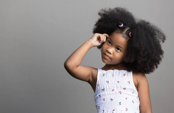 Porträt eines afroamerikanischen Mädchens mit lockigem Haar, das etwas denkt und nach oben schaut. - Foto, Bild