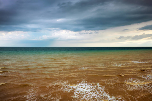 Dramatische Seelandschaft an bewölkten Tagen, endloser Meerblick bis zum Horizont. Wellen wirbelten den Lehm am Ufer auf - Foto, Bild