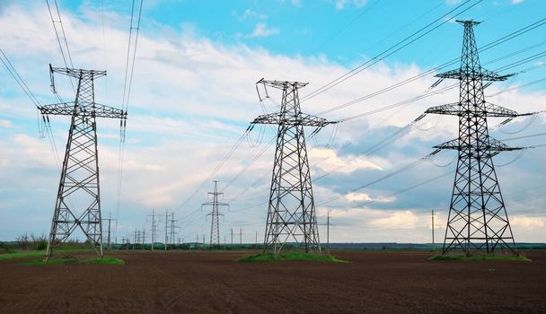 High voltage lines and power pylons in a flat and agricultural landscape on a sunny day with clouds in the blue sky.  - Photo, Image