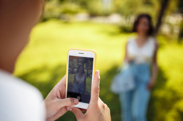 Крупним планом чоловік робить фотографії з мобільним телефоном жінки в парку. Весільні гості розважаються і фотографуються перед церемонією
 - Фото, зображення