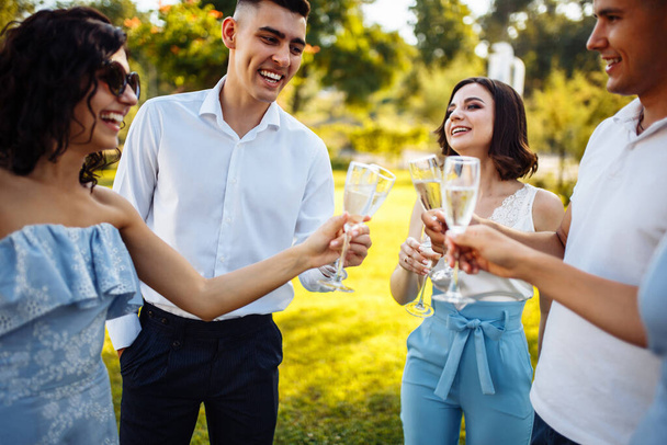 Wedding guests clinking glasses. Group of people enjoying champagne at wedding party. Guests toasting and cheering at stylish celebration - Valokuva, kuva