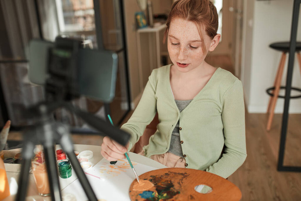 Ginger girl drawing with acrylic paints while broadcasting for her blog about art - Valokuva, kuva