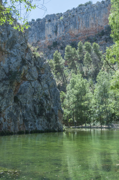 A vertical shot of a lake surrounded by rocky hills in  Monasterio de Piedra Park, Zaragoza, Spain - Фото, изображение