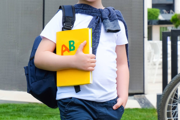 Schoolboy with a book in his hand on the street on the way to school. Back to school. - Foto, Bild