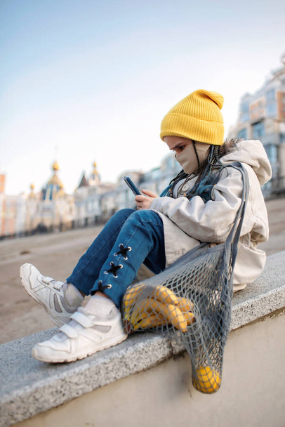 Preteen fille assise sur les escaliers de la rue et textos avec smartphone sur le chemin du shopping - Photo, image