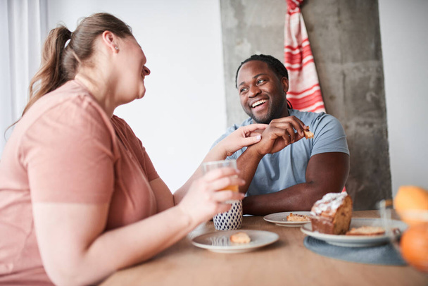 Couple enjoying breakfast together while drinking juice and eating cake - 写真・画像