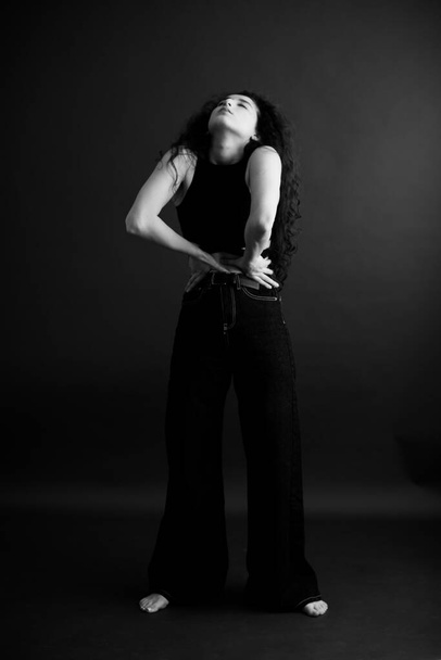 retrato simples e elegante de uma morena encaracolada, posando livre para a câmera, foco suave preto - Foto, Imagem