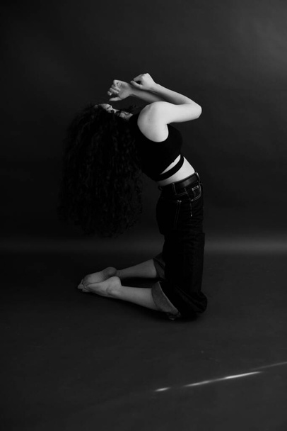 simple and stylish portrait of a curly brunette, free posing for the camera, black soft focus - Fotografie, Obrázek